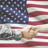 Soldier and doctor shaking hands with flag on background - United States